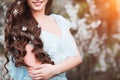 Happy beautiful young woman with long black healthy hair enjoy fresh flowers and sun light in blossom park at sunset. Royalty Free Stock Photo