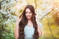 Happy beautiful young woman with long black healthy hair enjoy fresh flowers and sun light in blossom park at sunset. Royalty Free Stock Photo