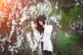 Happy beautiful young woman with long black healthy hair enjoy fresh flowers and sun light in blossom park at sunset. Royalty Free Stock Photo