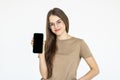 Happy beautiful young woman holding blank screen mobile phone and pointing finger over white background Royalty Free Stock Photo