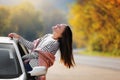 Happy beautiful young woman with long hair is looking out of the open window from car. Girl traveling in a car across Royalty Free Stock Photo