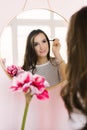 Happy beautiful young woman paints her eyelashes in front of the mirror at home while doing her makeup Royalty Free Stock Photo