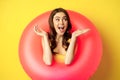 Happy beautiful young woman relaxing on summer vacation, wearing pink swim ring for beach holiday, standing against Royalty Free Stock Photo