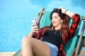 Happy beautiful young woman relaxing by the swimming pool with Royalty Free Stock Photo