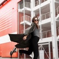 Happy beautiful young woman with a smile in a fashionable green coat walks in the city. Enjoying a walk.