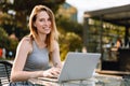 Happy beautiful young woman working on laptop in street cafe Royalty Free Stock Photo