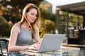 Happy beautiful young woman working on laptop in street cafe Royalty Free Stock Photo