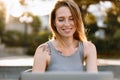 Happy beautiful young woman working on laptop in street cafe Royalty Free Stock Photo