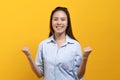 Happy beauty asian young woman showing excite expression. Shot in studio isolated on yellow background