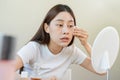 Happy beauty, beautiful asian young woman, girl looking in to mirror, holding cotton pad, applying facial wipe on her face, Royalty Free Stock Photo