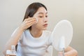 Happy beauty, beautiful asian young woman, girl looking in to mirror, holding cotton pad, applying facial wipe on her face, Royalty Free Stock Photo