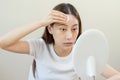 Happy beauty, beautiful asian young woman, girl looking in to mirror, holding cotton pad, applying facial wipe on her face, Royalty Free Stock Photo