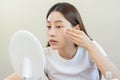 Happy beauty, beautiful asian young woman, girl looking in to mirror, holding cotton pad, applying facial wipe on her face, Royalty Free Stock Photo