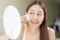 Happy beauty, beautiful asian young woman, girl looking in to mirror, holding cotton pad, applying facial wipe on her face, Royalty Free Stock Photo