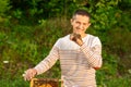 Happy beekeeper spends time in apiary. He holds a honeycomb full of bees. One hand is all in the bees Royalty Free Stock Photo