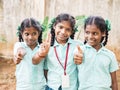 Happy best children friends girls classmates smiling showing thumb up gesture at the school. Multiethnic school kids enjoying