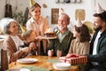 Happy big caucasian family wearing party hats celebrating grandfathers birthday indoors Royalty Free Stock Photo