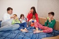Happy big family is having fun together in bedroom. Large family morning concept. Four kids with parents wear pajamas drink tea in