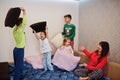 Happy big family is having fun together in bedroom. Large family morning concept. Mother with four kids wear pajamas fighting with
