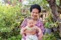 Happy big laughing child boy and senior woman holding adorable baby boy in flowery garden