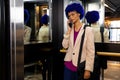 Happy biracial casual businesswoman with blue afro talking on smartphone in office elevator