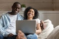 Happy biracial couple relax laugh using laptop at home Royalty Free Stock Photo