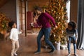 Happy biracial father and kids dance near fir tree Royalty Free Stock Photo