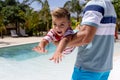 Happy biracial father and son playing by the swimming pool Royalty Free Stock Photo