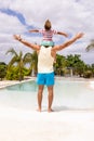 Happy biracial father and son widening arms by the swimming pool