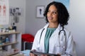 Happy biracial female doctor wearing sthethoscope, using tablet at doctor\'s office Royalty Free Stock Photo