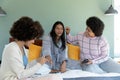 Happy biracial female friends applying make-up and painting fingernails of young woman on bed