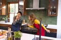 Happy biracial lesbian couple preparing meal having fun singing in kitchen Royalty Free Stock Photo