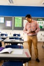 Happy biracial male teacher with tablet in elementary school classroom, copy space Royalty Free Stock Photo