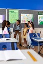 Happy biracial male teacher using tablet teaching children in elementary school class Royalty Free Stock Photo