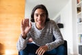 Happy biracial man sitting on sofa, having video call and waving Royalty Free Stock Photo