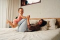 Happy biracial mother and daughter holding hands while playing on bed at home Royalty Free Stock Photo