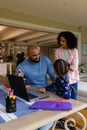 Happy biracial parents and daughter using laptop for schoolwork talking at home, copy space Royalty Free Stock Photo