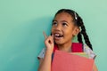 Happy biracial schoolgirl with books wearing school bag over blue background at elementary school Royalty Free Stock Photo