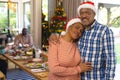 Happy biracial senior couple embracing and smiling at christmas meal with friends Royalty Free Stock Photo