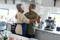 Happy biracial senior couple holding hands and looking at each other while dancing in kitchen Royalty Free Stock Photo