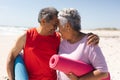 Happy biracial senior couple holding yoga mats touching foreheads of each other at beach Royalty Free Stock Photo