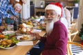 Happy biracial senior man celebrating with friends at christmas dinner in sunny dining room Royalty Free Stock Photo