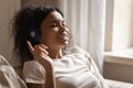 Happy biracial woman in Bluetooth headphones relax at home Royalty Free Stock Photo