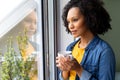 Happy biracial woman holding cup of coffee and looking out window at home Royalty Free Stock Photo