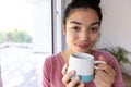 Happy biracial woman holding cup of coffee at sunny home Royalty Free Stock Photo
