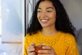 Happy biracial woman holding cup of tea and looking out window at home Royalty Free Stock Photo