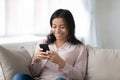 Happy biracial woman relax on sofa using smartphone Royalty Free Stock Photo