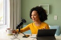 Happy biracial woman using headphones, tablet and microphone podcasting from home Royalty Free Stock Photo