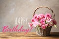 Happy Birthday! Beautiful pink Eustoma flowers in wicker basket on wooden table