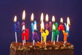 Happy Birthday Brownie Cake with Peanuts, Salted Caramel and Colorful Burning Candles on the Violet Background. Copy Space for Royalty Free Stock Photo